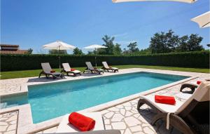 a swimming pool with chairs and umbrellas in a yard at Villa Inga in Buje