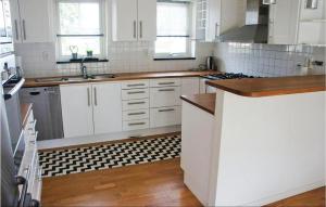 a kitchen with white cabinets and a black and white tile floor at Cozy Home In Nybrostrand With Sauna in Glemminge