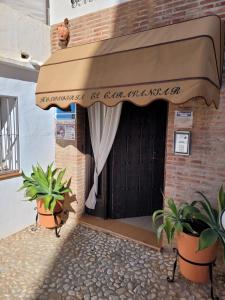 un edificio con una puerta con plantas delante de él en Hospedería El Caravansar, en Frigiliana