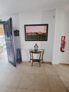 una habitación con una mesa y una pintura en la pared en Hospedería El Caravansar, en Frigiliana
