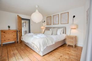 a bedroom with a large white bed and a wooden floor at Beautiful Town House in Stratton, Bude, Sleeps 8 in Bude