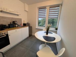 a small kitchen with a white table and a window at FC-Apartmenthaus Falkensee mit großem Garten und PKW Stellflächen in Falkensee