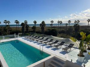 piscina con sedie e spiaggia di Templo Sotogrande a Sotogrande