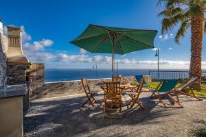 カニコにあるVilla Araújo da Costa by Holiday Rental Madeiraのテーブルと椅子、パラソルと海