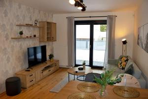 TV a/nebo společenská místnost v ubytování ENJOYHARRACHOV Atraktivní klidné studio 3 v centru Harrachova s parkováním, velkou terasou, Wifi-WLAN, SAT zdarma, možností dobíjení auta, výhledem do zahrady a na romantický kostelík
