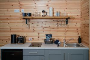 a kitchen with a sink and wooden walls at Mount Ephraim Glamping Pods in Hernehill
