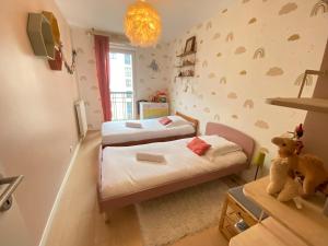 a small bedroom with two beds and a stuffed bear at La Casita Mexicana - Kids Friendly by So Homy- 3 Bed Room - 6 PAX in Saint-Ouen