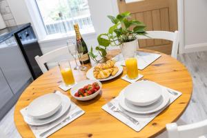 a wooden table with plates and bowls of fruit and glasses of orange juice at 2BR Modern Hebden Hideaway, Canal side, Stylish and Cosy in Hebden Bridge