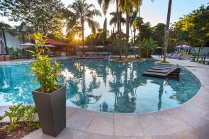 a large swimming pool with palm trees and a playground at Hotel Saint George in Puerto Iguazú