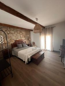 a bedroom with a bed and a stone wall at Casa Rural Mateo Corchero in Villanueva de la Sierra