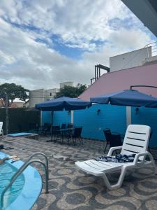 a group of chairs and umbrellas next to a pool at Casa Pérolas do Mar in Balneário Camboriú