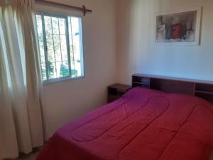 Un dormitorio con una cama roja y una ventana. en La Quinta 2, en Maipú