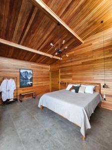 una camera con un grande letto e pareti in legno di Khaya Chalés - Chalés de Luxo na Serra para Casais com Hidro a Jaboticatubas Altre 64 foto