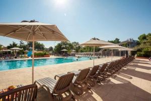 カネ・アン・ルシヨンにあるCamping 4 étoiles - Piscine - ccaaeagのスイミングプールの横の椅子とパラソル