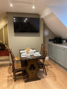 a dining room table with chairs and a television on the wall at Trowel and Hammer, Flat 2 in Cotton +7 photos