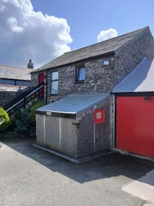 a brick house with a red door and a garage at The Chisel Coach House at The Bettle and Chisel in Delabole