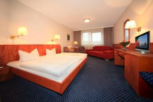 ein Hotelzimmer mit einem großen Bett und einem roten Sofa in der Unterkunft Hotel-Restaurant Seegarten Quickborn in Quickborn