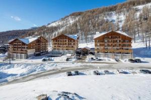 a group of buildings in the snow with a waterfall at Les chalets du verdon in Allos