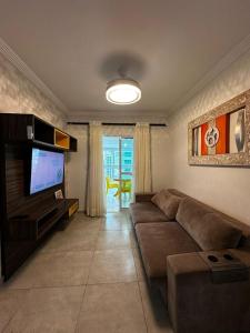 a living room with a couch and a flat screen tv at Apartamento completo no Centro- Mongaguá Pé na areia in Mongaguá