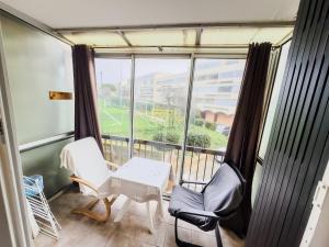 un balcone con due sedie, un tavolo e una finestra di La petite frégate Studio idéal curiste a Balaruc-les-Bains