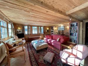 a living room with a red couch and chairs at 300 years old Chalet close to Center ski-lift in Chateau-d'Oex