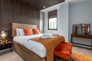 a bedroom with a large bed with orange pillows at Palm Tree House Apartments in Farnborough +274 photos