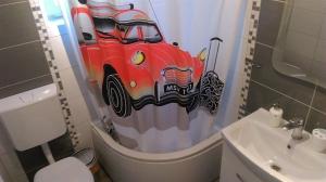ein Bad mit einem Duschvorhang mit einem Auto darauf in der Unterkunft Apartments and Room Rest in Sumartin