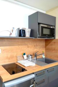 a kitchen counter with a sink and a microwave at La Belle vigne - Chablis Centre in Chablis