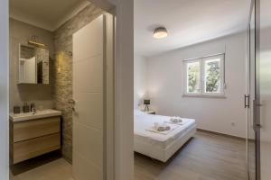 a white bathroom with a bed and a sink at Nikolica Apartments Pelješac in Potomje