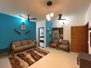 een woonkamer met blauwe muren en een bank en stoelen bij Paradise Pool Villa 30min from Ecity Garden2BHK in Hosūr +54 foto's