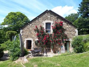 an old stone house with red flowers on it at ArcenFrance in Sussac