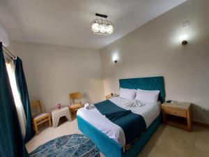 a bedroom with a blue bed and a chandelier at Anubis kingdom pyramids view in Cairo