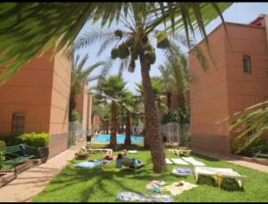 a group of people laying on the grass under palm trees at Riad Izza in Marrakesh