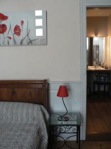 ein Schlafzimmer mit einem Bett und einem Tisch mit einer Lampe in der Unterkunft La Terrasse de la Grand'Rue - chambre d'hôtes - in Mugron