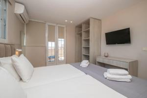 a bedroom with a white bed with a tv on the wall at Anadiomeni Pool & Beach Apartments by "elite" in Zakynthos