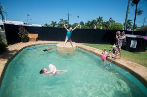 a woman is jumping into a swimming pool at Cool Palms Motel in Mackay