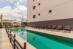 a swimming pool with chairs next to a building at Studio 1204 Com Vista Livre e Andar Alto in São Paulo