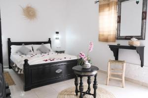 a bedroom with a black bed and a table with flowers on it at Elegant Marrakech Villa with Optional Heated Pool for Ultimate Relaxation in Touggana +98 photos