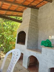 an outdoor pizza oven with a white chair next to it at house with pool and 5 bedrooms in São Pedro da Aldeia