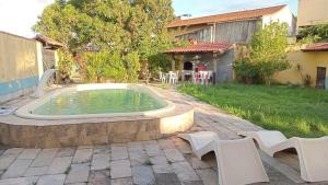 a pool in a yard with white chairs and a house at house with pool and 5 bedrooms in São Pedro da Aldeia