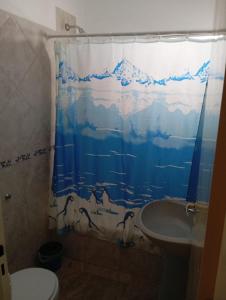 een badkamer met een douchegordijn, een toilet en een wastafel bij Atalaya in Puerto Madryn +12 foto's