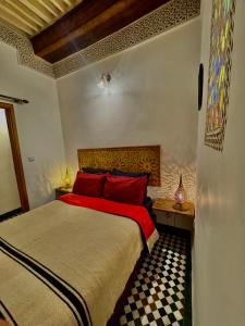 a bedroom with a bed with red pillows and a window at Appartement khmissa in Fès al Bali