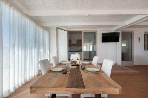 a dining room with a wooden table and white chairs at Le Secche Suite & House 1 by Salento Prime in Torre Pali 