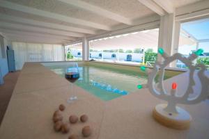 a glass of wine sitting on a table next to a swimming pool at Le Secche Suite & House 2 by Salento Prime in Torre Pali 