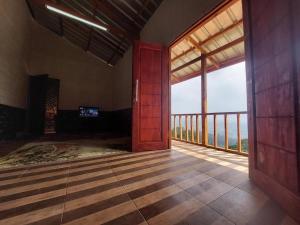 Pondok CipasebanにあるVilla Zoya Montanaの大きな窓付きのバルコニーが備わる空の客室です。