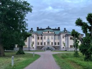 a large white house with a green roof at Salsta slotts paviljong in Vattholma