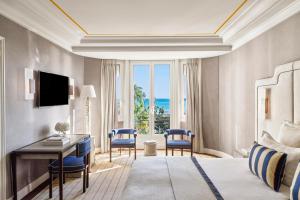 a hotel room with a bed and a desk and chairs at Hôtel Barrière Le Majestic Cannes in Cannes