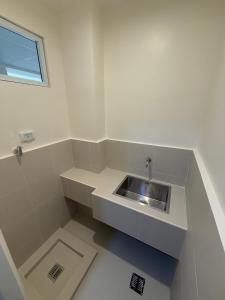 a white bathroom with a sink and a window at Rafflesia - Studio Type Room in Davao City +10 photos