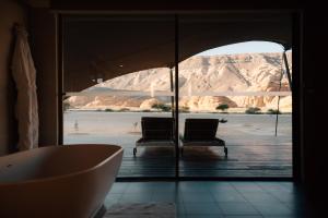 a bathroom with a tub and a view of the water at Ashar Tented Resort in Al-ʿUla +31 photos