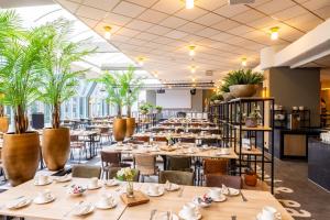 a dining room with tables and chairs and plants at Wunderland Kalkar in Kalkar